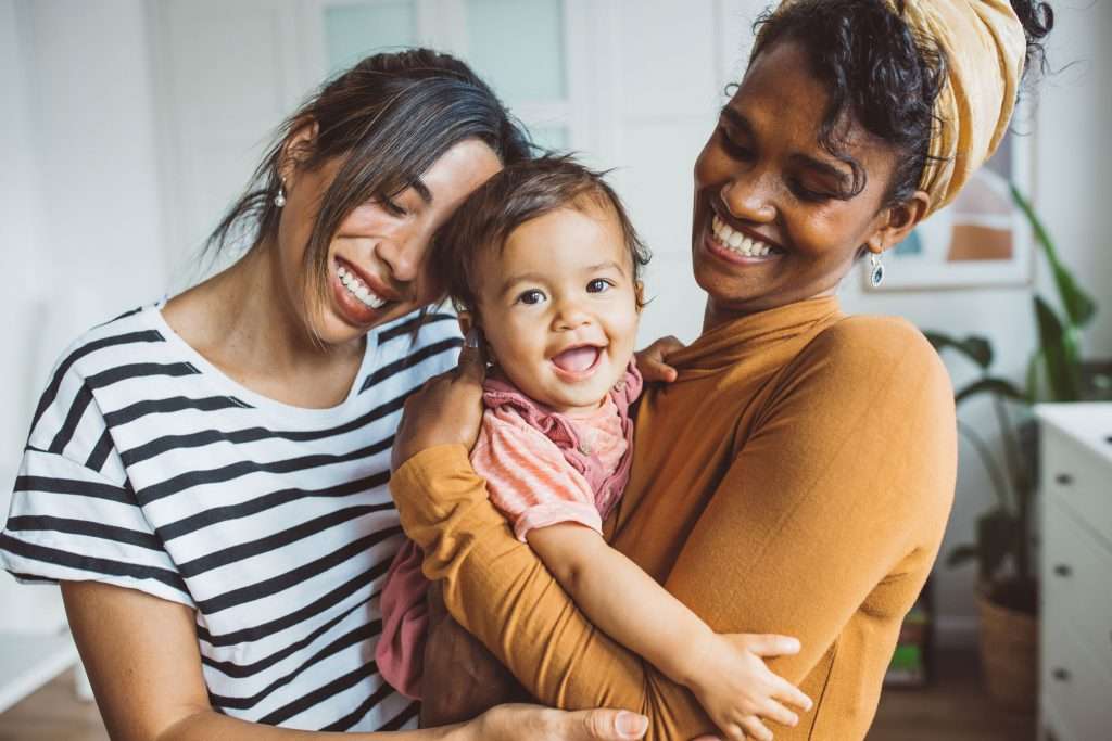 Photo of two young women, one white and one African American, holding a small child.