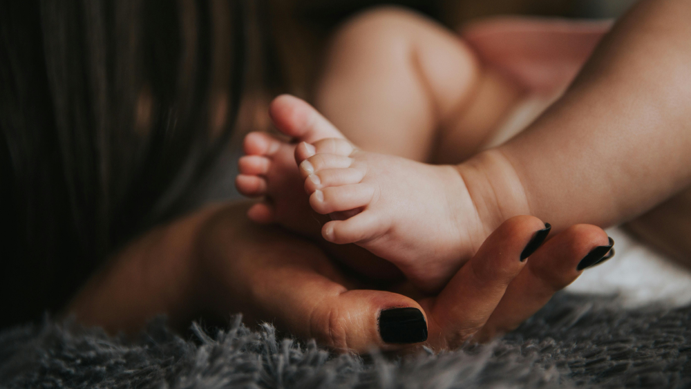 Mothers hands holding infants foot in posed image